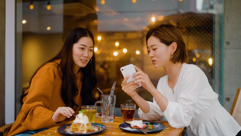 Two women eating and looking at the phone screen