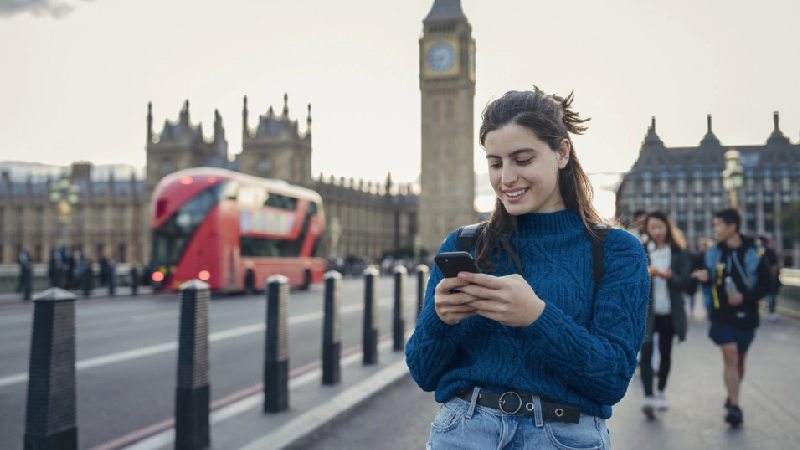 Woman checking her phone near Big Ben in London