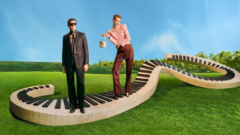 Fashion models posing on a winding piano walkway in a green field under a blue sky